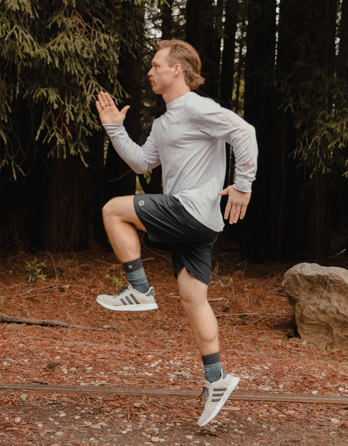 A man running on a forest trail wearing Baja Llama Relaxplorations black athleisure shorts, demonstrating the active performance fit.