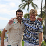 Two smiling male models walking with arms around each other outdoors wearing Baja Llama apparel including the Reptile Wrangler cream western button-up shirt with embroidered gecko accents