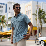 Model wearing the Baja Llama Road Runner blue western snap button-up shirt with embroidered shoulder details and light trousers on a city street