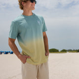 Model wearing the Baja Llama Rock On Cactus embroidered ombre heavy tee and sunglasses on a sunny beach