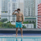 Turquoise green men's solid print swimsuit with Baja Llama embroidered logo 