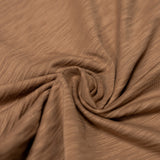 An extreme close-up  shot of the brown pima slub knit fabric from the Baja Llama La Republica Embroidered Pocket Tee, showing the highly textured, slub cotton gathered into a soft swirl.
