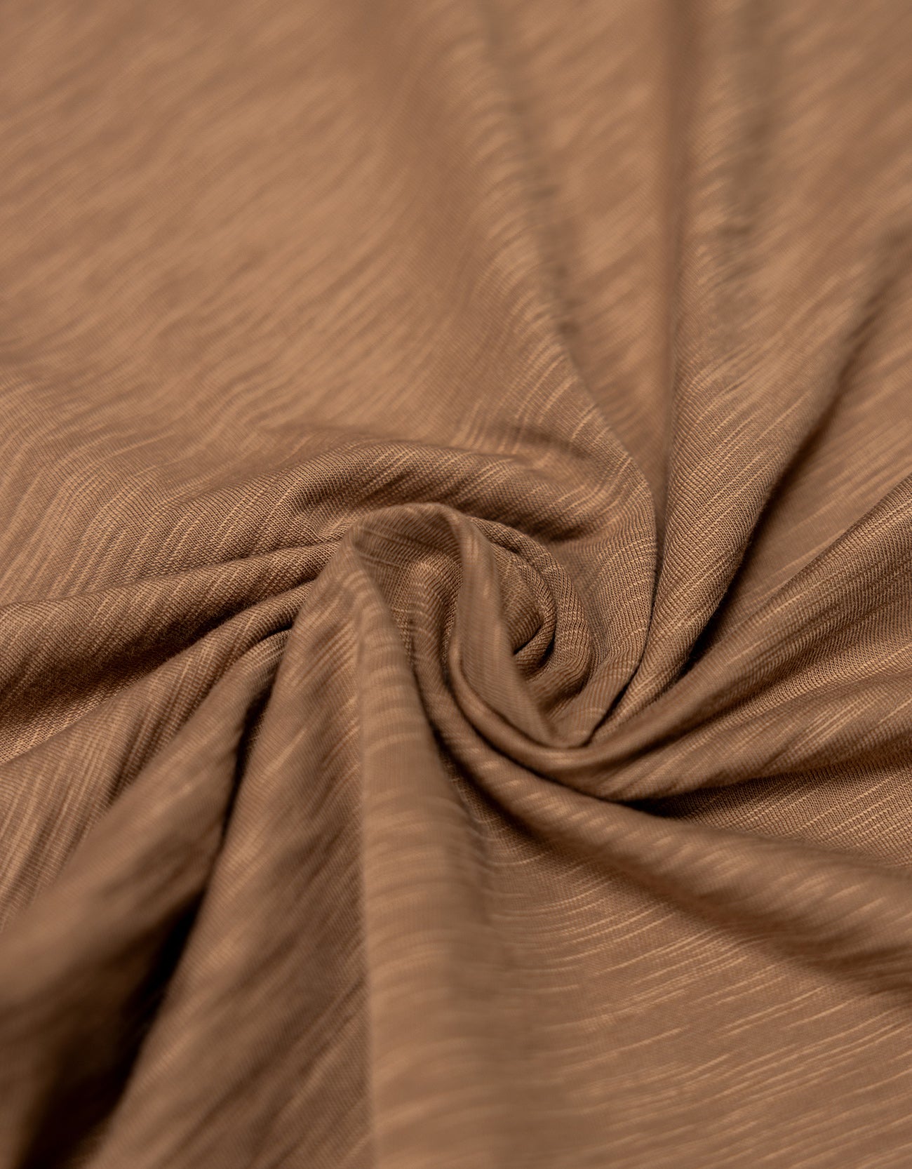 An extreme close-up  shot of the brown pima slub knit fabric from the Baja Llama La Republica Embroidered Pocket Tee, showing the highly textured, slub cotton gathered into a soft swirl.