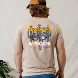 Tranquilo Amigos graphic tee by Baja Llama. This tan-colored tee features a vibrant and playful design with two sloths lounging in hammocks attached to cacti, accompanied by 'Tranquilo Amigos' text. Made from soft fabric with a relaxed fit, perfect for a laid-back, adventurous vibe.