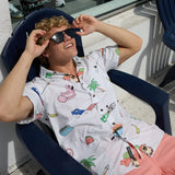 Model wearing Baja Llama The BBQ Shirt 7-Seas relaxed fit button-up and sunglasses while relaxing in a chair.