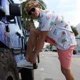 Baja Llama The BBQ Shirt 7-Seas Relaxed Fit Button Up white short sleeve shirt worn by a model tying his shoe next to a truck.