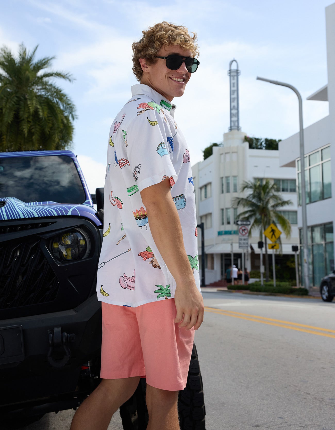Baja Llama The BBQ Shirt 7-Seas Relaxed Fit Button Up white short sleeve shirt styled on a model standing by a custom vehicle.
