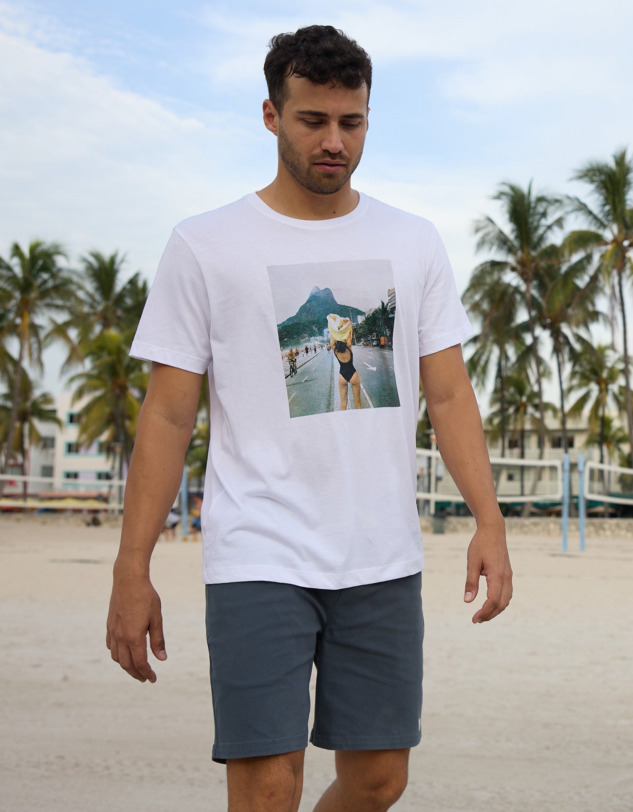 Baja Llama The Girl In Ipanema Primo Graphic Tee white short sleeve t-shirt worn by a model on a tropical beach.