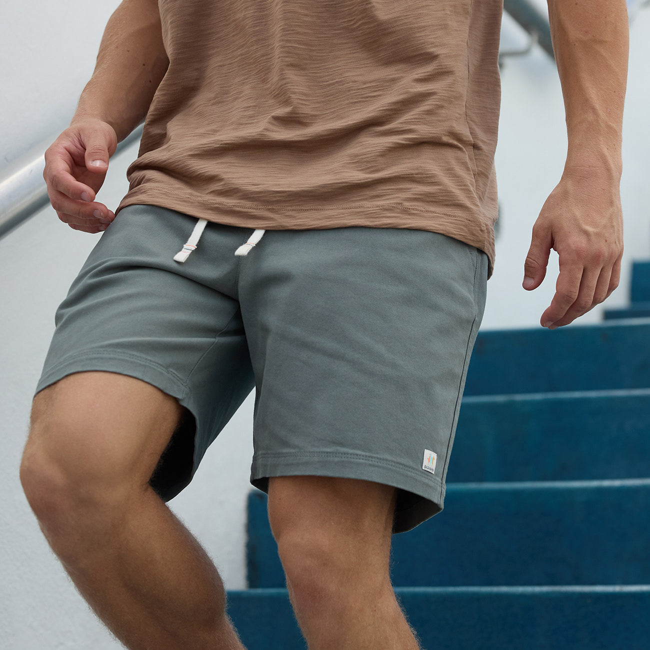 Baja Llama Too Easys Seafoam Green Stretch Cotton Shorts worn by a man walking down stairs