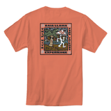 Baja Llama coral tee with vibrant back graphic that says “Trip With Your Friends” showing a dancing palm tree and mushroom. Bold, fun, and built for good times.