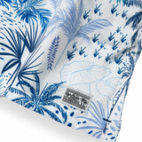 White men's swim trunks featuring tropical palm trees and taro in different hues of blue.