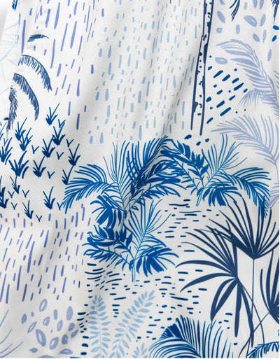 White men's swim trunks featuring tropical palm trees and taro in different hues of blue.