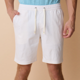 Person wearing white shorts with a beige background