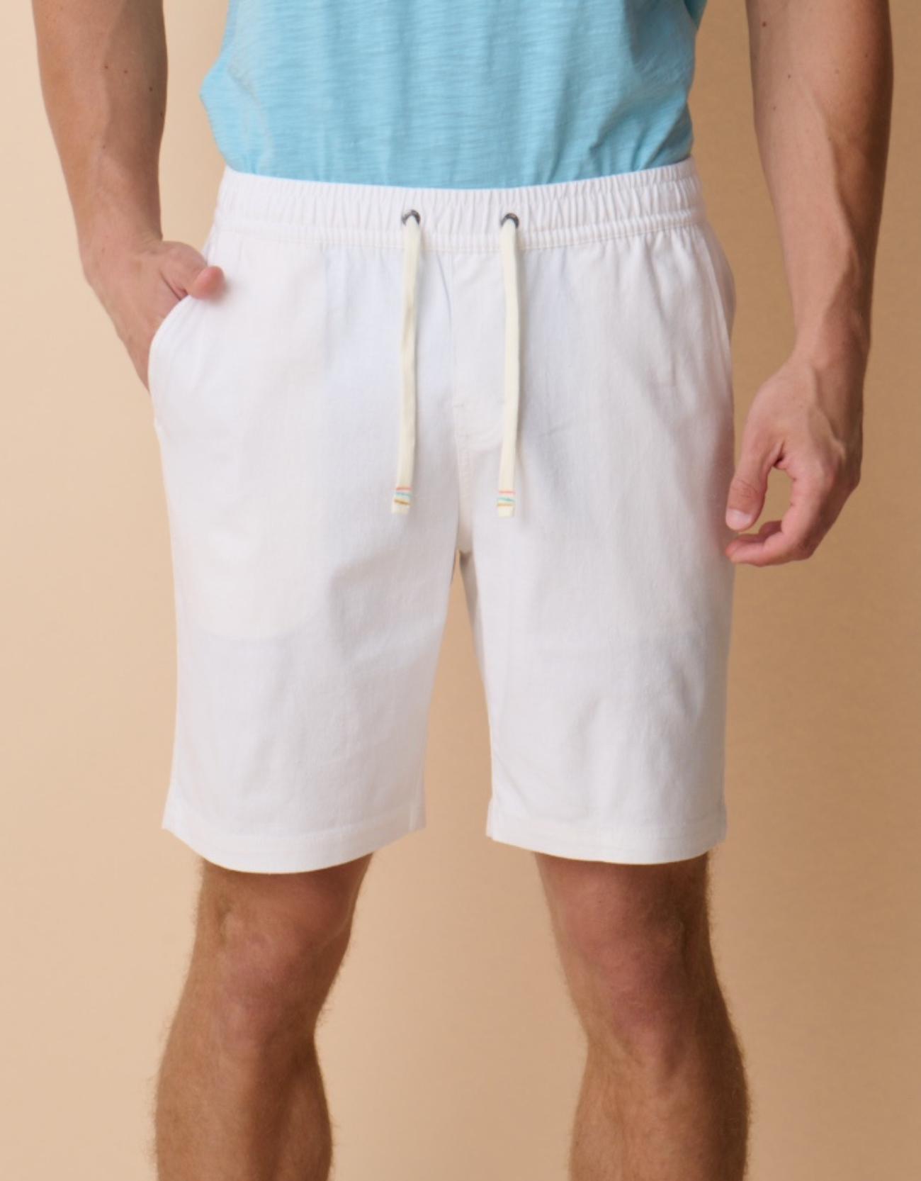 Person wearing white shorts with a beige background